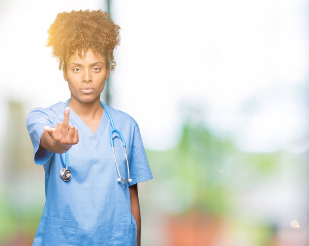junge afrikanisch-amerikanische Ärztin über isolierten Hintergrund zeigt Mittelfinger, unhöflich und unhöflich fuck off Ausdruck - Foto, Bild
