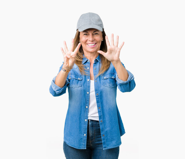 Belle femme d'âge moyen portant une casquette de sport sur fond isolé montrant et pointant vers le haut avec les doigts numéro neuf tout en souriant confiant et heureux
. - Photo, image