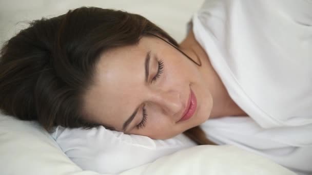 Primer plano hermosa mujer durmiendo acostado en ropa de cama blanca
 - Metraje, vídeo