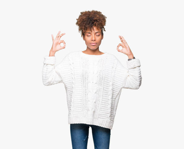 Beautiful young african american woman wearing winter sweater over isolated background relax and smiling with eyes closed doing meditation gesture with fingers. Yoga concept. - Foto, afbeelding
