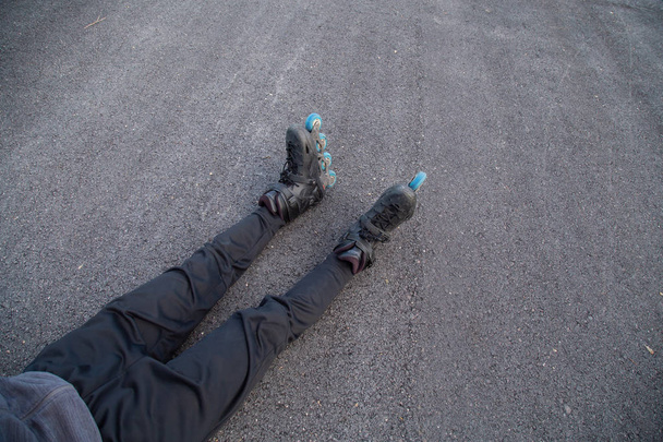 Ноги людини з роликовими ковзанами, що лежать на дорозі
 - Фото, зображення