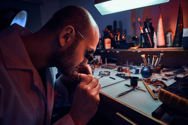 Фокусированный мастер работает на клиентских часах в своей мастерской
. - Фото, изображение