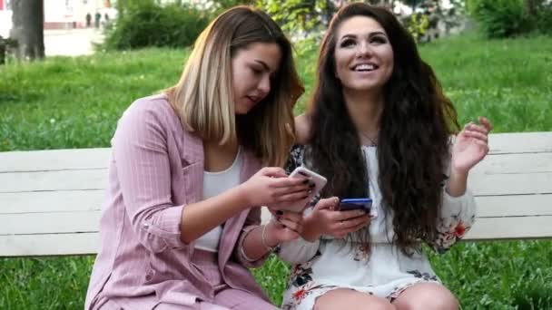 Blondynka i brunetka kobiety używają telefonu komórkowego - Materiał filmowy, wideo
