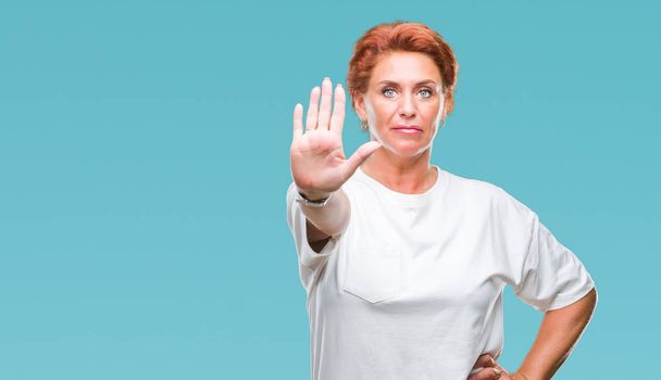 Atrractive senior caucasian redhead woman over isolated background doing stop sing with palm of the hand. Warning expression with negative and serious gesture on the face. - Fotoğraf, Görsel
