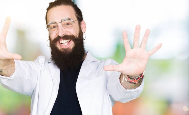 Doktor terapeuta ember hosszú haja és a medve visel fehér kabátot mutatja, és rámutatva ujjak száma tíz, miközben mosolyogva magabiztos és boldog. - Fotó, kép