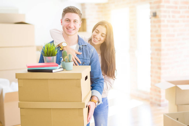 Hermosa pareja joven sonriendo en amor sosteniendo cajas de cartón
,  - Foto, Imagen