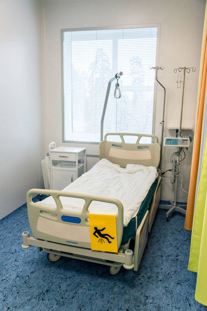 εσωτερικό σε νοσοκομείο, κρεβάτι νοσοκομείου με πρόσθετα ράφια και εξοπλισμό στο δωμάτιο - Φωτογραφία, εικόνα