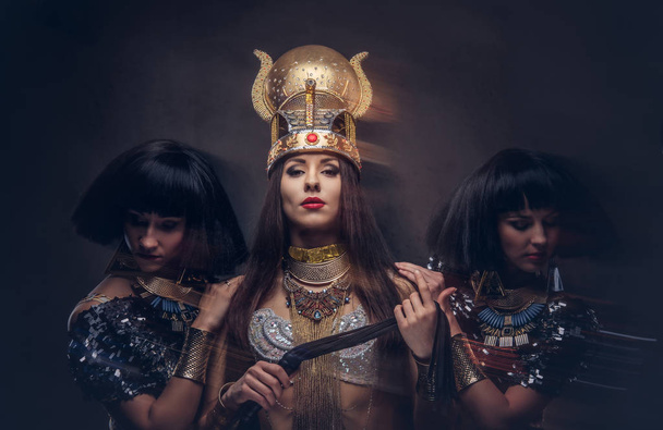 Retrato de la altiva reina egipcia en un antiguo disfraz de faraón con dos concubinas
. - Foto, Imagen