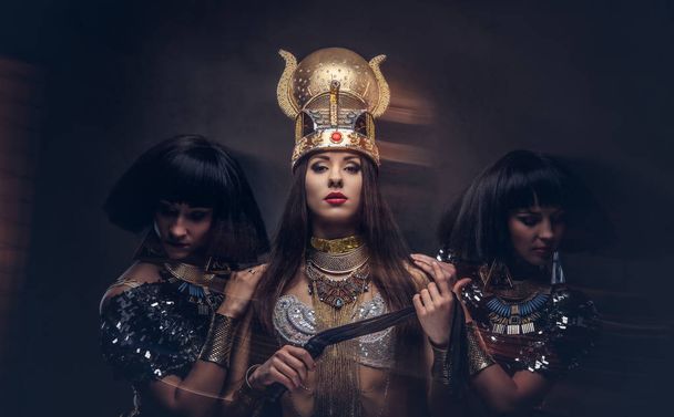 Портрет надменной египетской царицы в костюме фараона с двумя наложницами
. - Фото, изображение