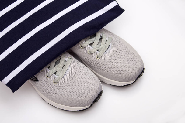 Αθλητικά παπούτσια σε ριγέ φόντο. Παιδικά παπούτσια μόδας σε ένα μαύρο και άσπρο ριγέ φόντο. Γυναικεία αθλητικά παπούτσια. Αθλητικό στυλ. Ένδυση για αθλήματα - Φωτογραφία, εικόνα