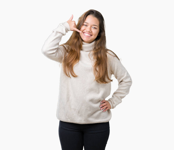 Young beautiful brunette woman wearing turtleneck sweater over isolated background smiling doing phone gesture with hand and fingers like talking on the telephone. Communicating concepts. - Foto, afbeelding