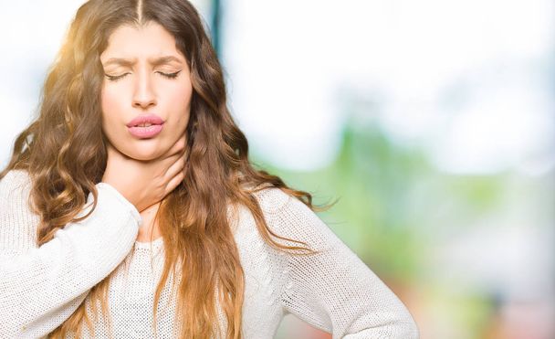 Mladá krásná žena nosí bílý svetr dotyku bolestivý krk, bolest v krku, chřipka, Hrouda a infekce - Fotografie, Obrázek