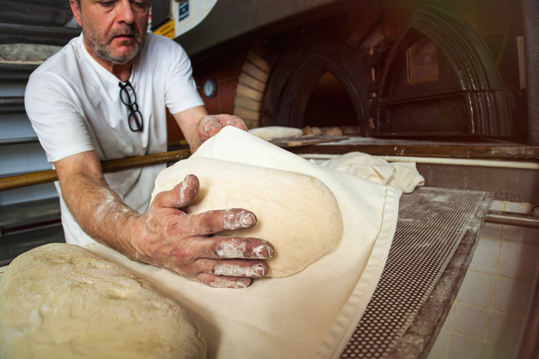 Egy pékség fatüzelésű kemencében sült kenyér előállítása. - Fotó, kép