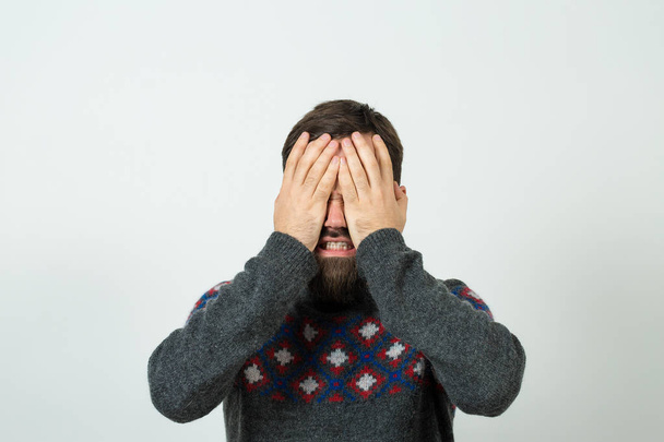 young bearded man covering face on white background  - Photo, image