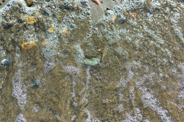 Kleurrijke stenen op het strand van het meer Issyk Kul. Rust in Kirgizië. Het tij is aan het meer. Natte kiezels. - Foto, afbeelding