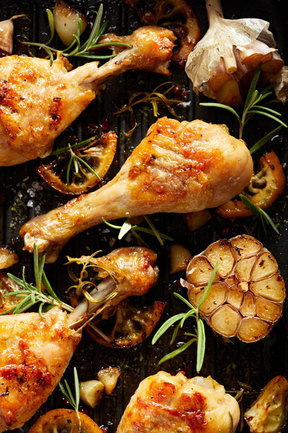 Grilled chicken. Grilled chicken legs, drumsticks with addition, garlic, lemon and fresh rosemary on grill plate.Grill food - Photo, Image