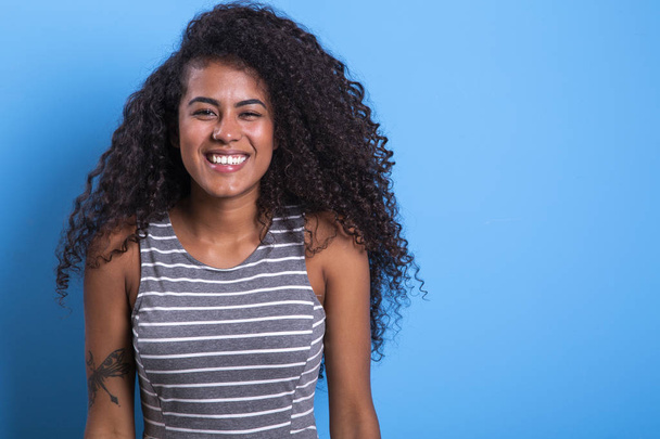 Portrait of smiling black woman with afro hairstyle on blue background - Imagem. - Foto, afbeelding