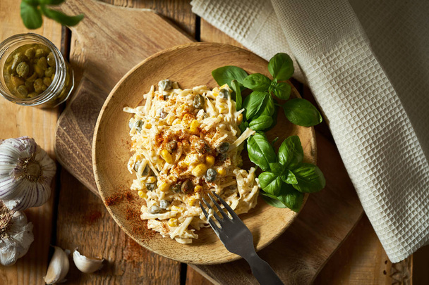 Salad of grated cheese with capers and corn  with basil on wooden table - Photo, Image