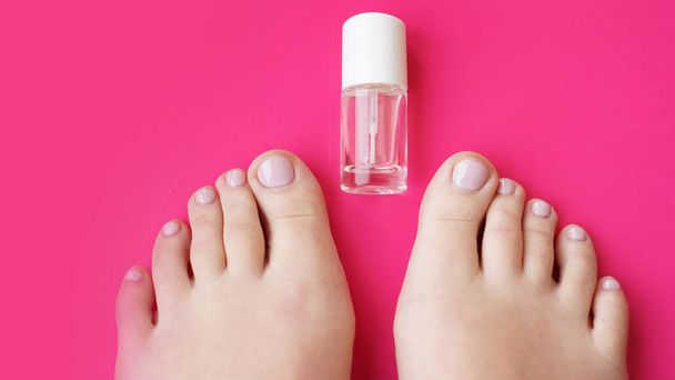 Pedicure with transparent nail polish on pink background - Фото, зображення