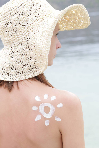 Femme avec écran solaire en forme de soleil sur son épaule, concept de protection de la peau
 - Photo, image