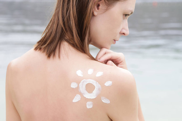 彼女の肩の上に太陽の形の日焼け止めを持つ女性,皮膚保護コンセプト - 写真・画像