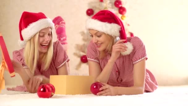 Weihnachtsstimmung. zwei glückliche Mädchen genießen Silvesterstimmung. Frohe Weihnachten und Winterurlaub. Freundin spielt neben dem Weihnachtsbaum. - Filmmaterial, Video