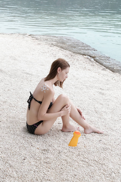 Γυναίκα εφαρμογή αντηλιακή κρέμα στα πόδια της, έννοια φροντίδας του δέρματος - Φωτογραφία, εικόνα