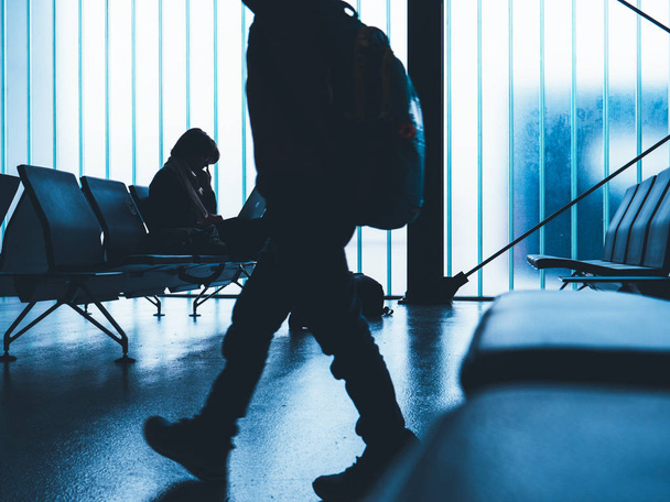 Man walking in front of business woman working in empty airport terminal - Photo, Image