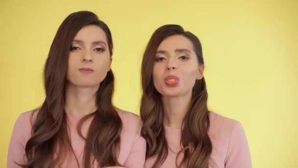 Tweeling meisjes blazen kauwgom in bubbels. - Video