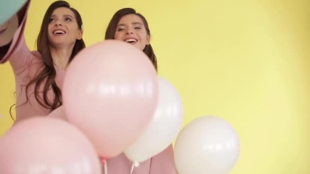 Renkli balonlarla oynayan pembe elbiseler içinde güzel ikizler - Video, Çekim