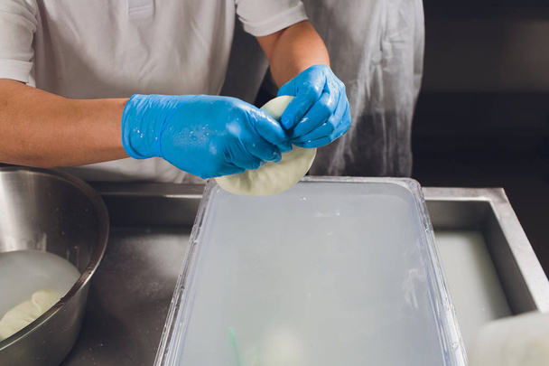 Artisan cheesemaker cuts the mozzarella with hands. - Valokuva, kuva