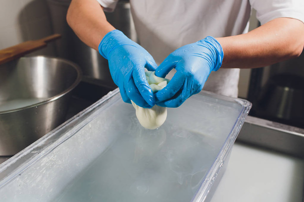 Artisan cheesemaker cuts the mozzarella with hands. - Foto, immagini