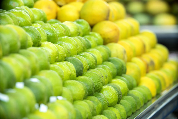 pile of a large number of green fresh limes for sale in supermarket. - Foto, afbeelding