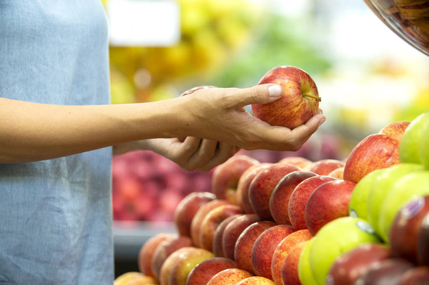 Woman's hand choosing red apple in supermarket  - Fotoğraf, Görsel