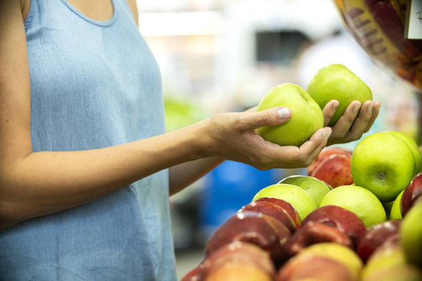 Woman's hand choosing green apple in supermarket  - Fotó, kép