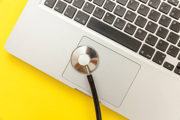 Stetoskop klawiatura laptop komputer izolowane na żółtym tle. Nowoczesna technika informacyjna medyczna i koncepcja postępu SOFWARE. Diagnostyka i naprawa komputerów i gadżet - Zdjęcie, obraz