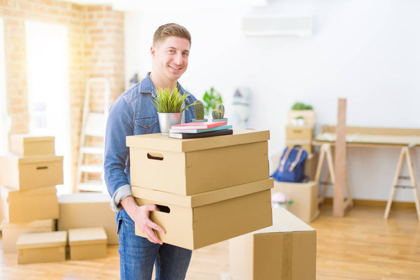 Handsome young man smiling happy moving to a new home, very exci - 写真・画像