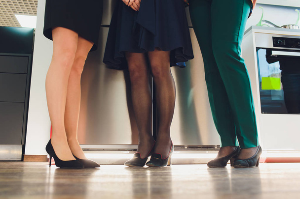 Legs of businesspeople. Woman wearing skirt, stockings and high heels, man wearing dark trousers and shoes. - Foto, afbeelding