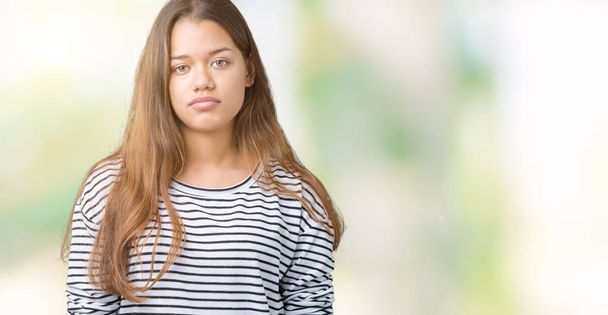 Young beautiful brunette woman wearing stripes sweater over isolated background Relaxed with serious expression on face. Simple and natural looking at the camera. - Foto, immagini