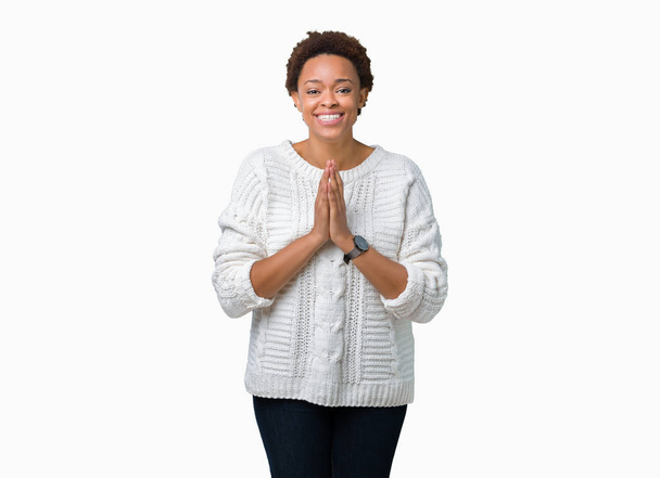 Linda jovem afro-americana vestindo suéter sobre fundo isolado orando com as mãos juntas pedindo perdão sorrindo confiante
. - Foto, Imagem