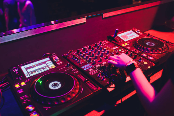 DJ turntable console mixer controlling with two hand in concert nightclub stage. - Photo, Image