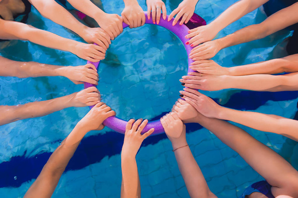 women trains in aqua aerobics, learn to swim. circle team hands - Photo, Image