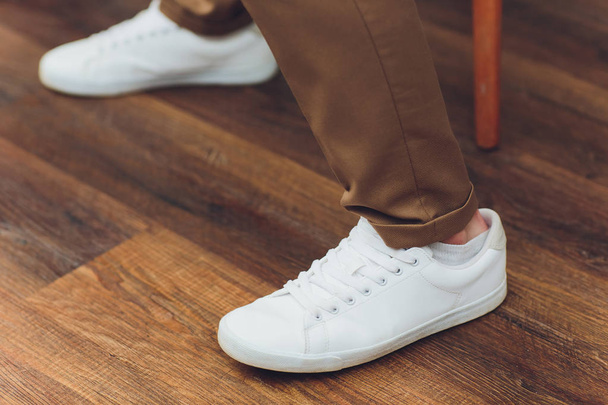 White sneakers,lower half, legs, on wooden boards. - Foto, afbeelding