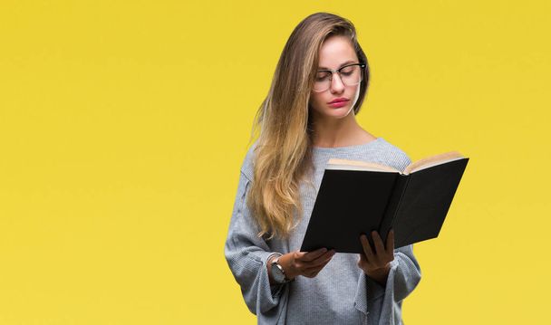 Young beautiful blonde woman reading a book over isolated background with a confident expression on smart face thinking serious - Photo, image