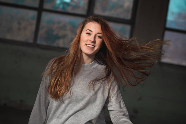 Cute, redhead teenage girl in gray sweater swinging her long hair - Foto, immagini