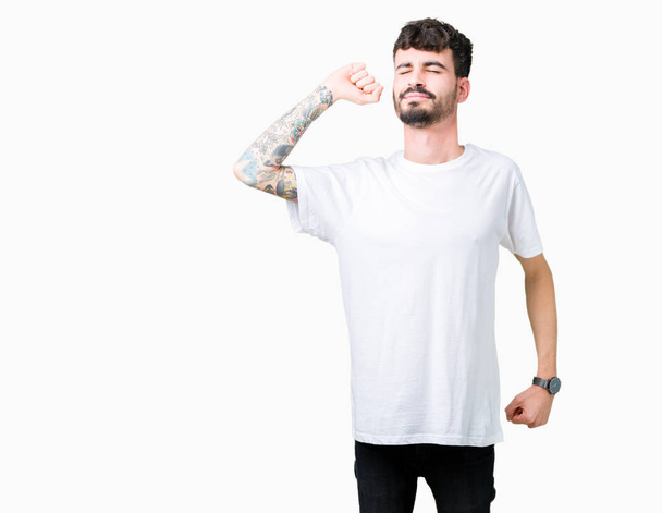 Young handsome man wearing white t-shirt over isolated background stretching back, tired and relaxed, sleepy and yawning for early morning - Photo, Image