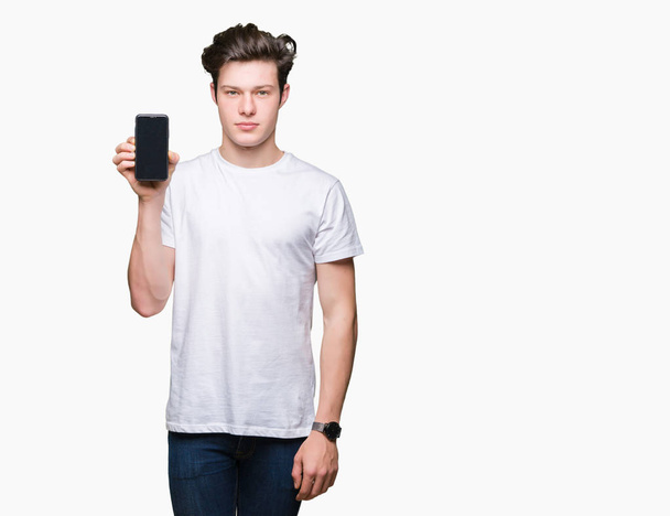 Młody człowiek pokazując ekran smartfona na białym tle z pewnym wyrazem na inteligentne myślenie twarzy poważne - Zdjęcie, obraz
