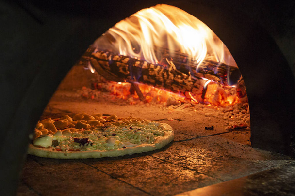 Italian pizza inside a wood oven  - Valokuva, kuva