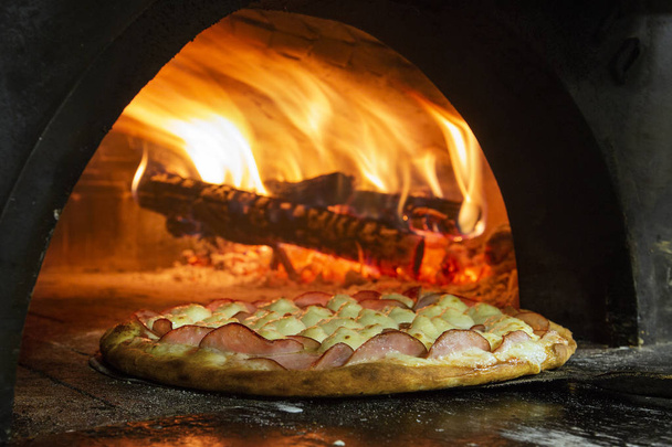 Italian pizza inside a wood oven  - Photo, image