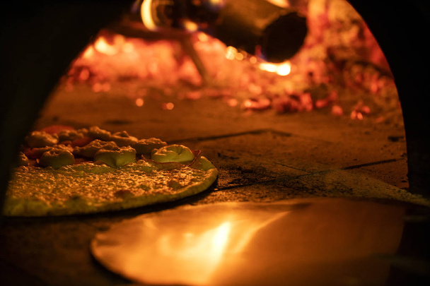 Italian pizza inside a wood oven  - Фото, изображение